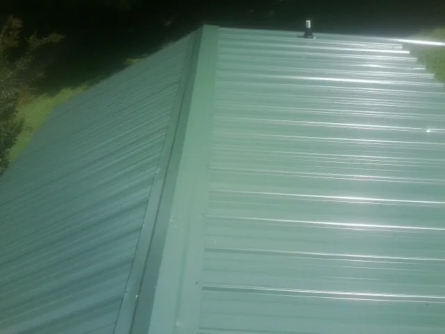 New green metal panels meeting at the ridge of a roof — Flat Roof Repair work by our crew in Walton